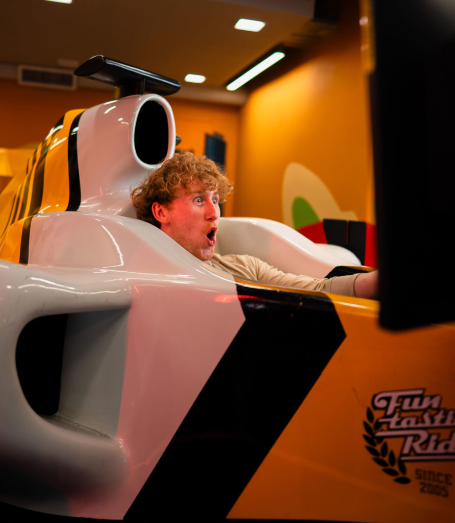 Person enjoying a thrilling ride in a car simulator arcade game.