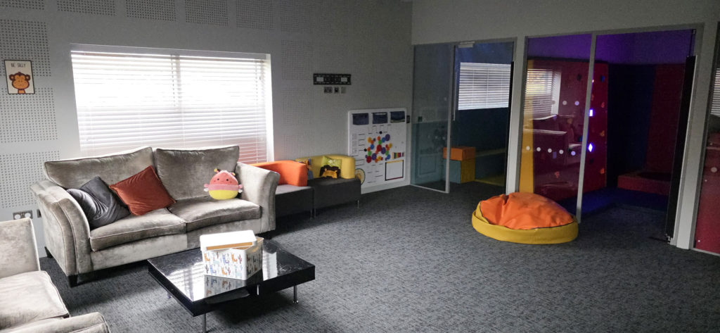Modern playroom with cozy seating, colorful decor, and interactive wall panels for a fun, engaging environment.